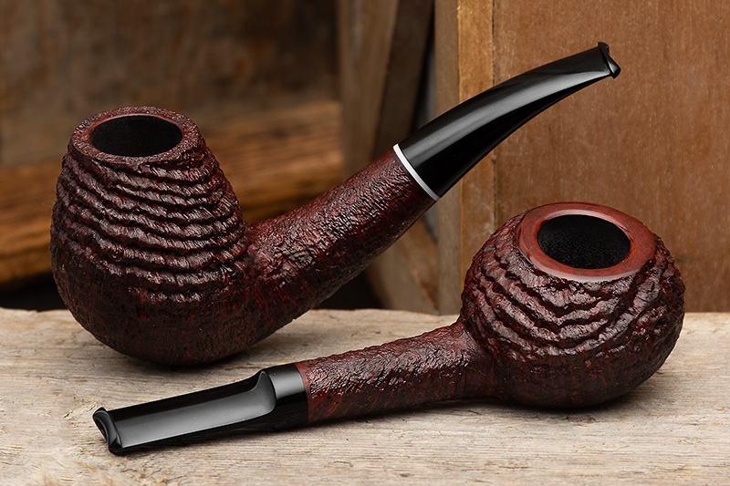 Two Il Cerchio ring-blasted pipes, a bent egg and a straight apple, on a weathered wooden plank