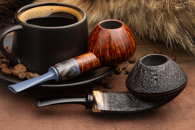 Sabina Santos smooth straight-grain pipe and sandblasted pipe beside a cup of black coffee