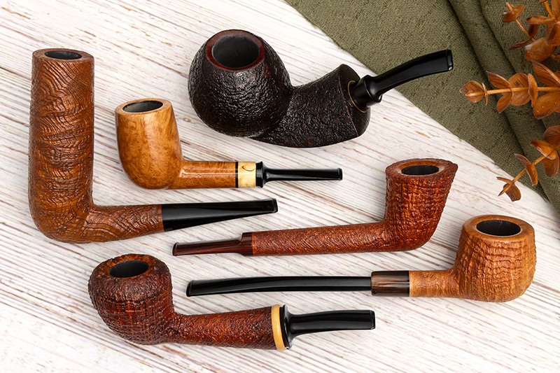 Six Smokin' Barrel Briars pipes in sandblasted and smooth finishes on whitewashed wood